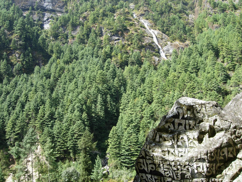 A köveken nepáli írás, a háttérben egy vízesés